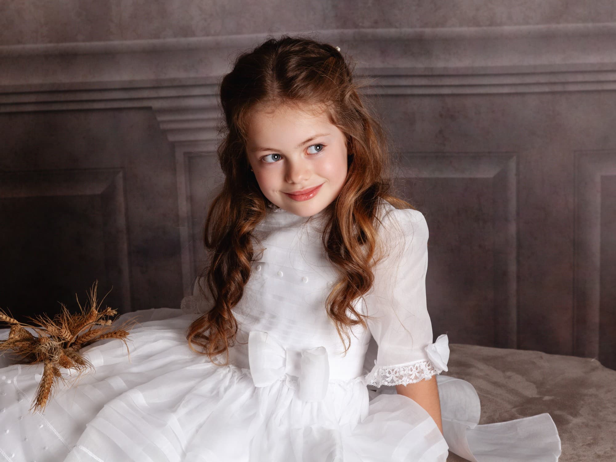 Niña con vestido de comunión sonriendo en el estudio